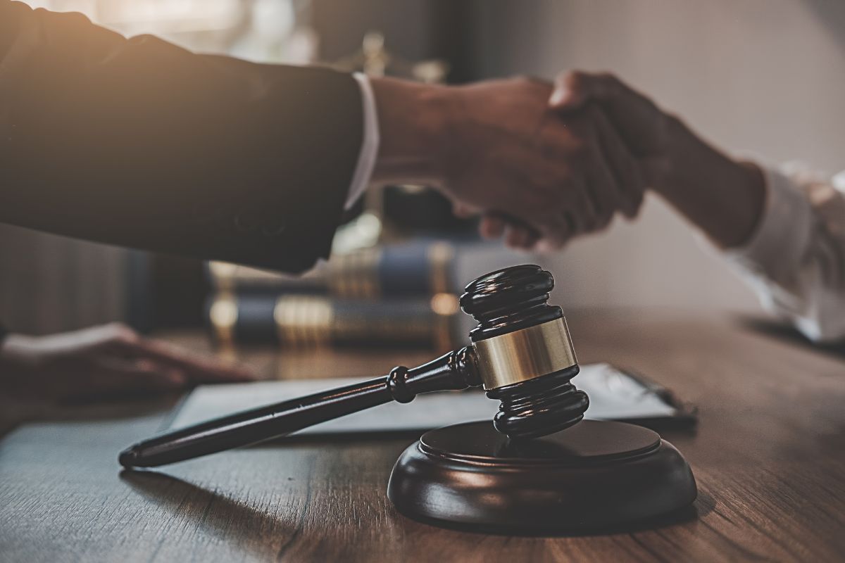 Legal agreement handshake with gavel on desk